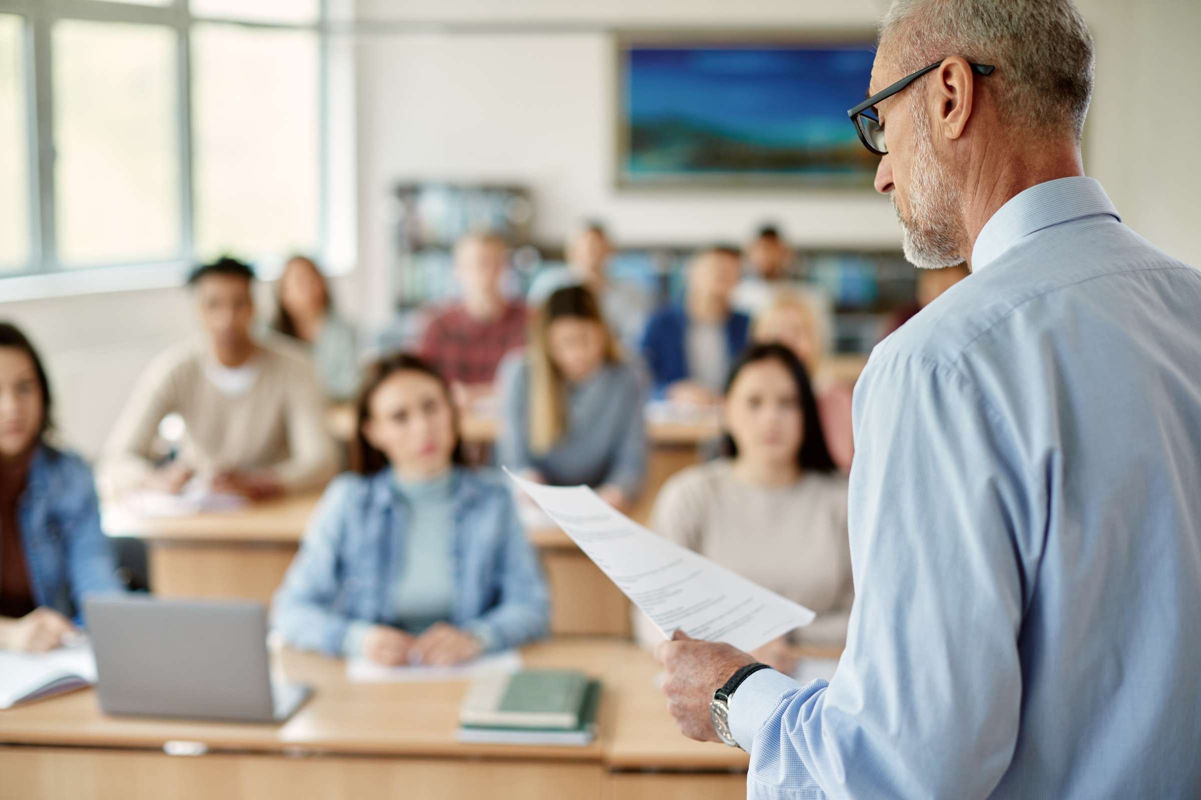 Instructor reading a paper in front of a college class