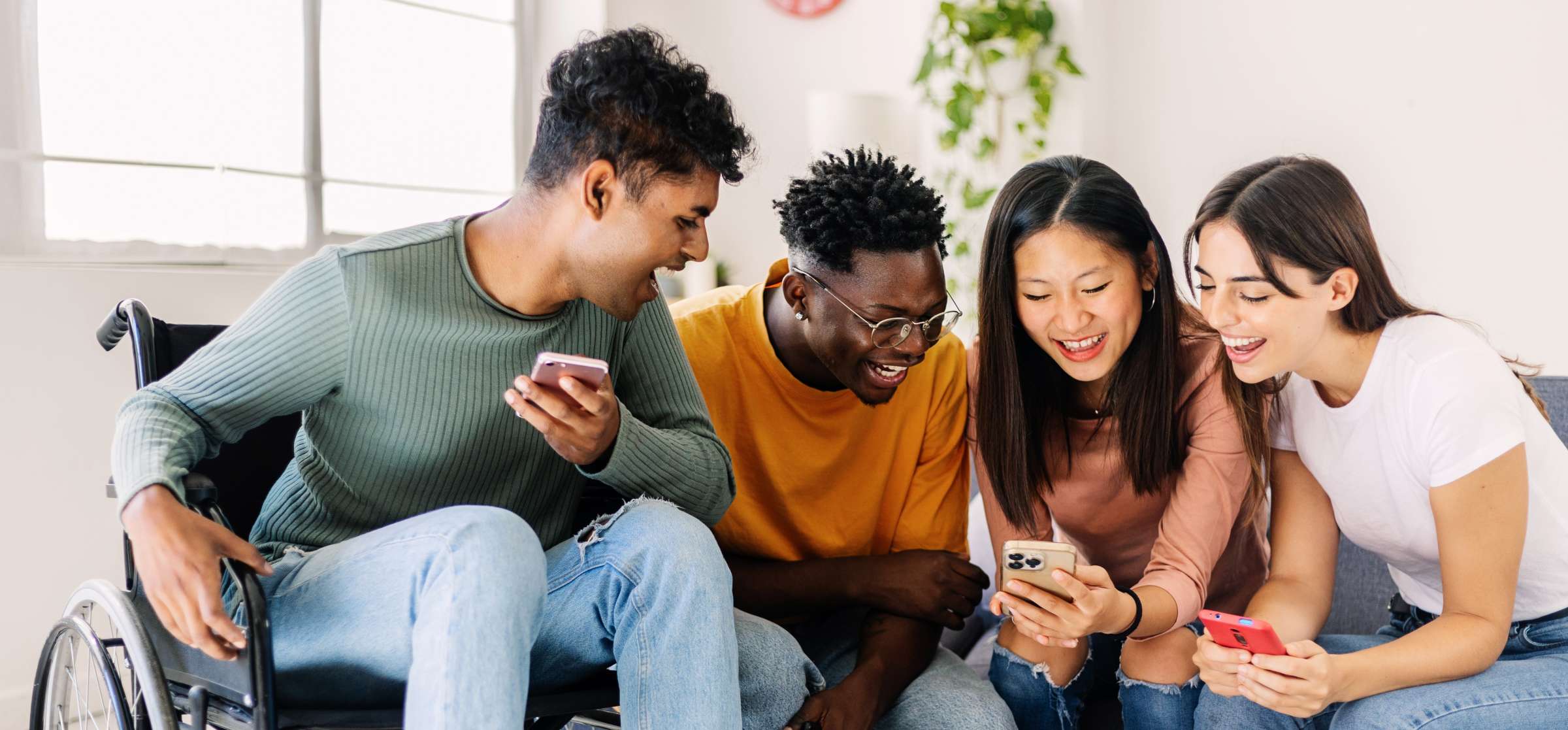 Group of students laughing and looking at one person's phone