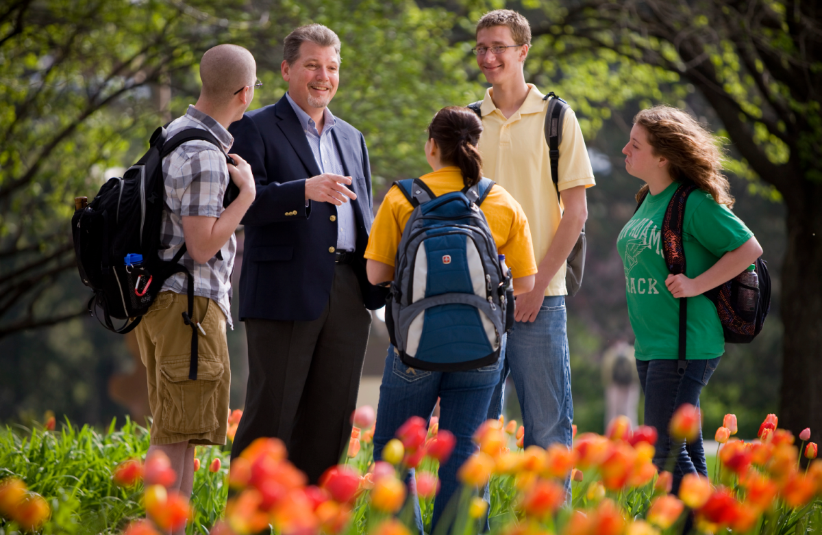 Professor talking with students in front of a tulip garden
