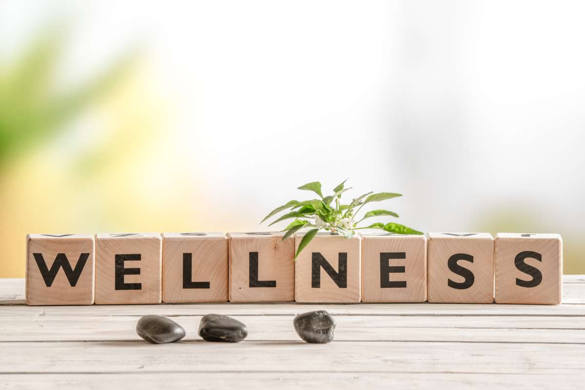 Photo of wooden blocks, each with a black letter printed on them spelling out wellness