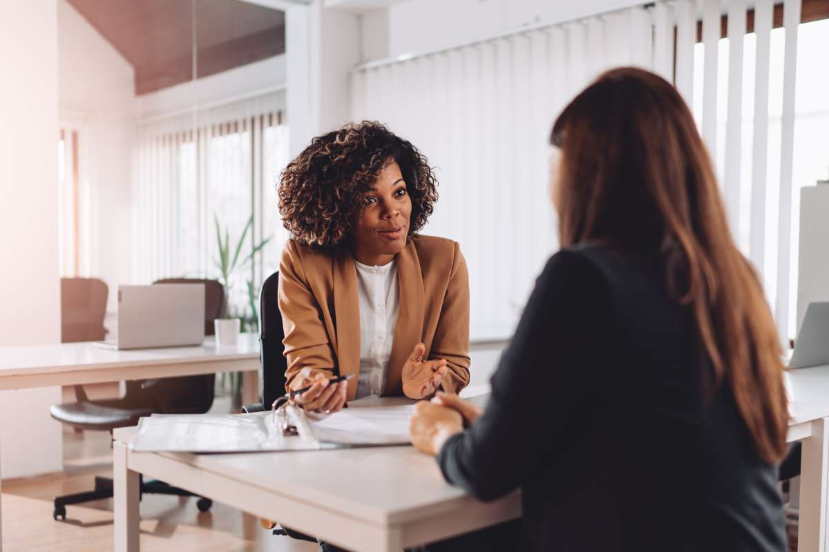Coordinator sitting across a desk from a student, talking in a meeting