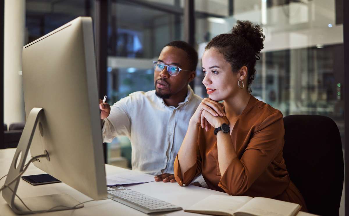 Two coordinators looking over documentation on a computer discussing a case