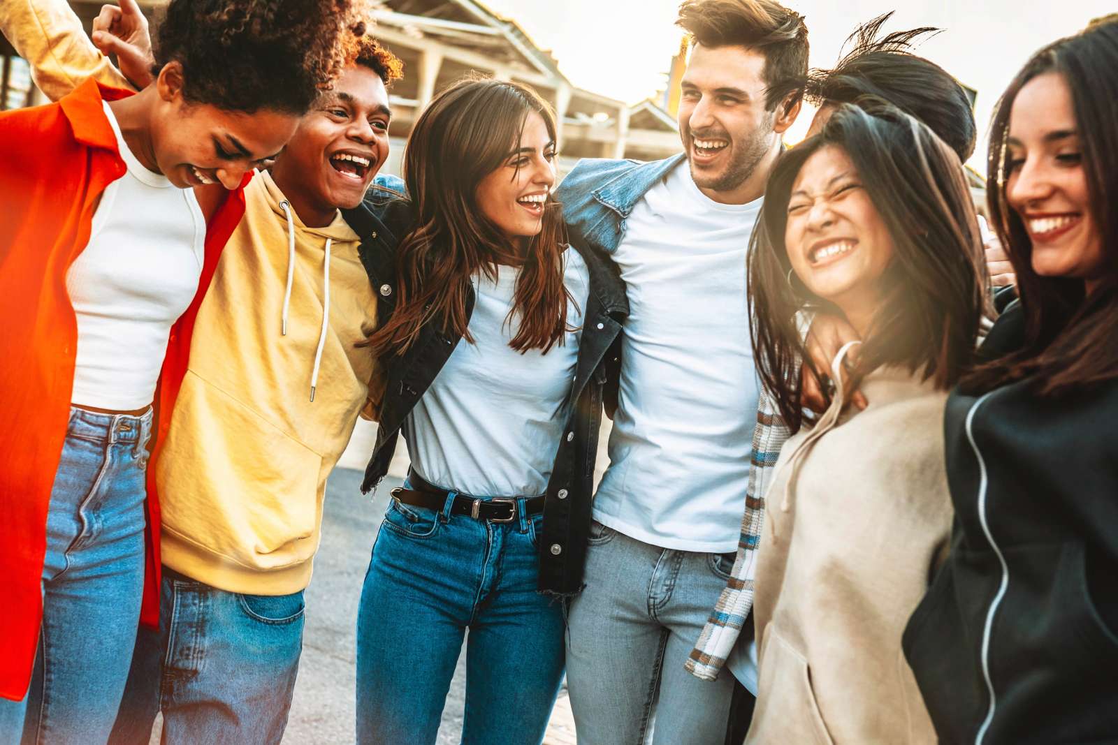 5 Students with arms around each other's shoulders laughing and smiling