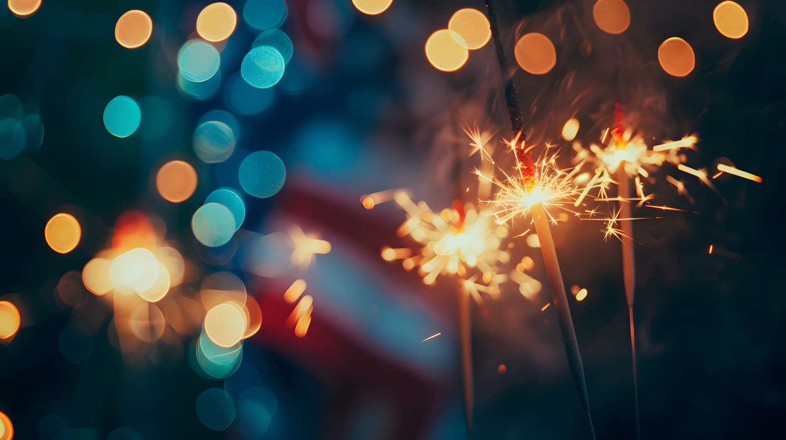 Three sparklers in focus with a dark red/white/blue out of focus background